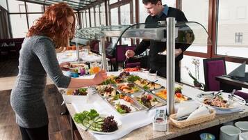 A buffet setup with various food items and a server attending to guests.