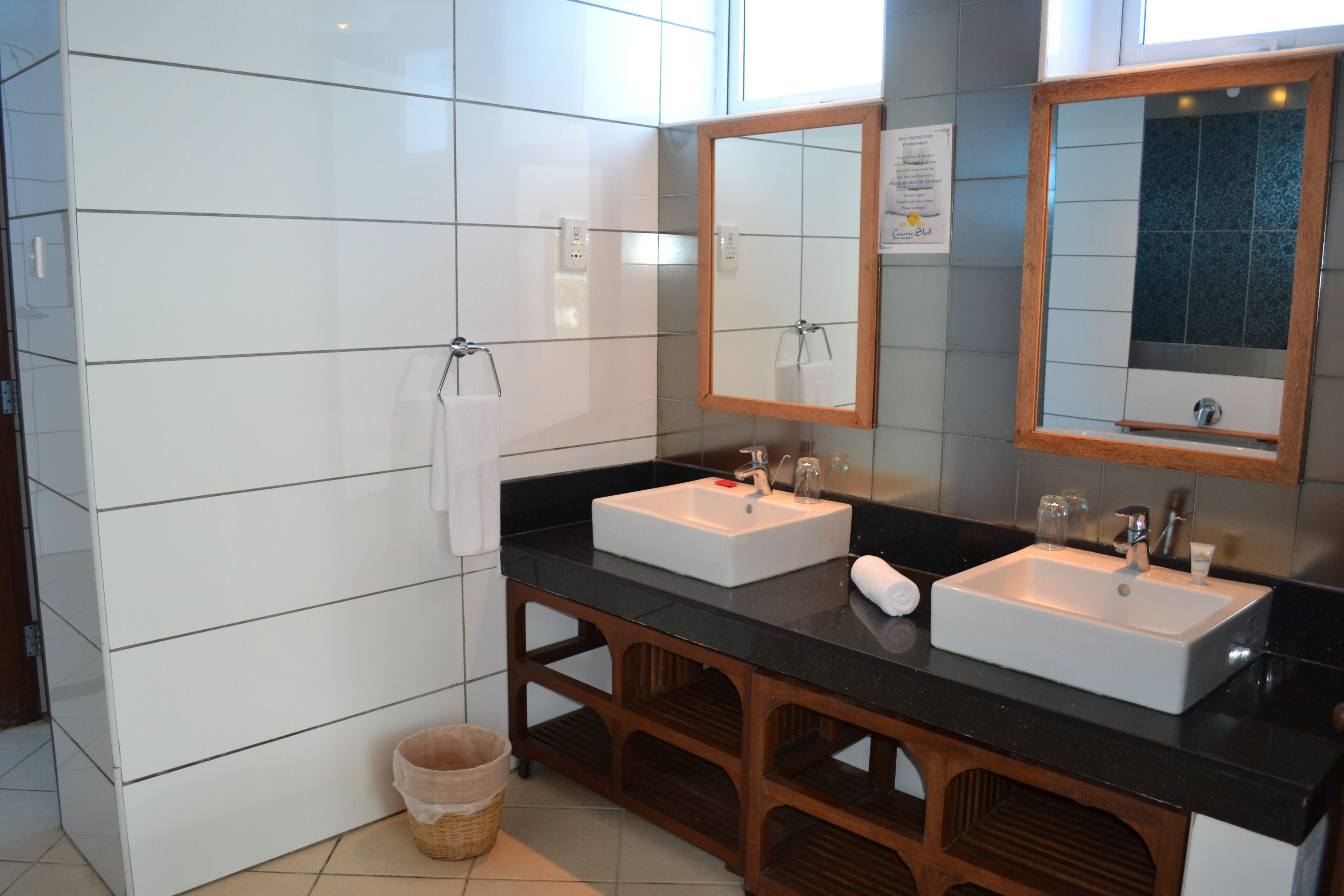 Un bagno con due lavabi, uno specchio e un mobiletto in legno.