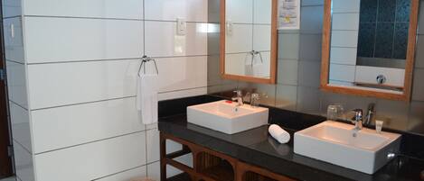 Un bagno con due lavabi, uno specchio e un mobiletto in legno.