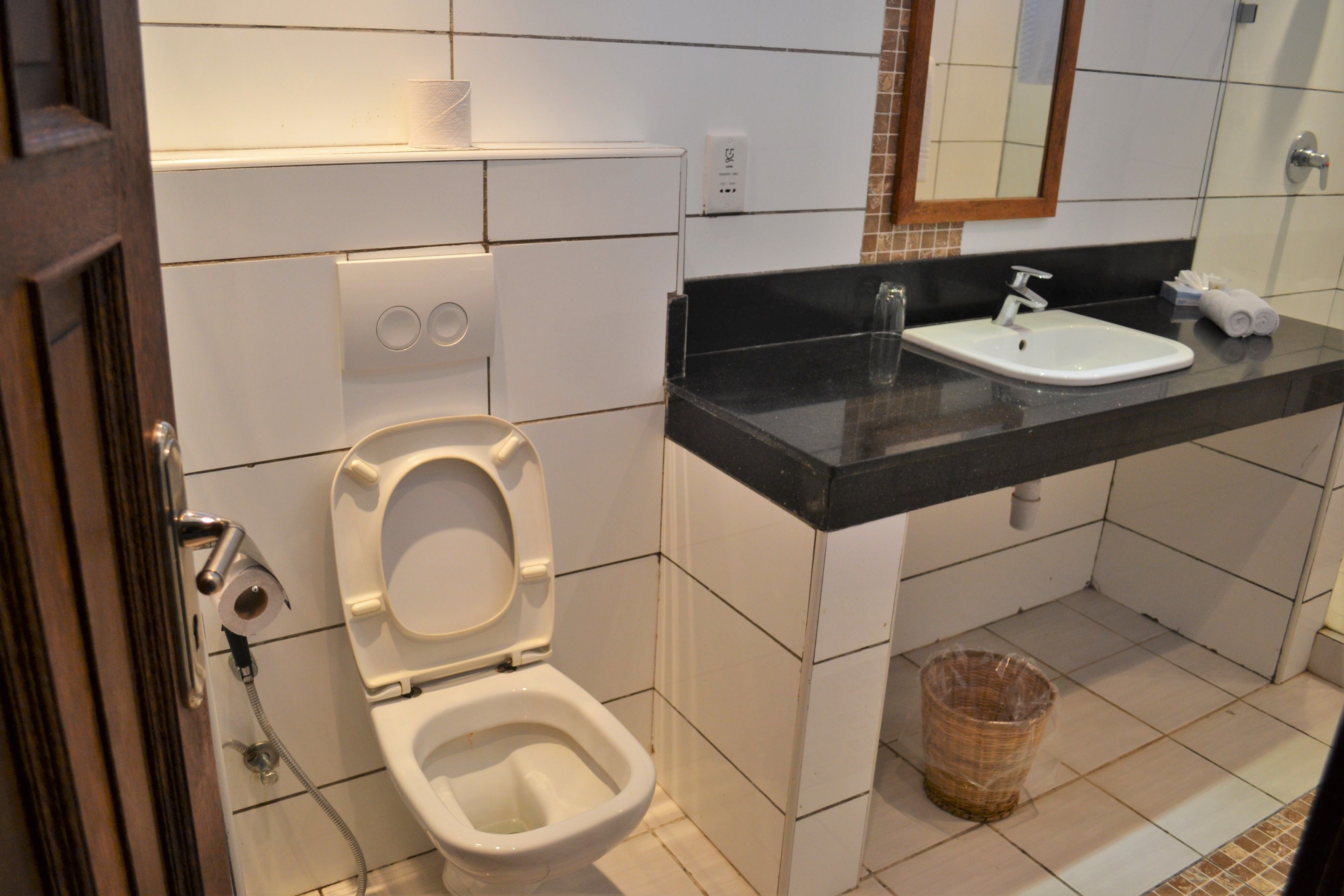 A bathroom with a toilet, sink, and a trash bin.
