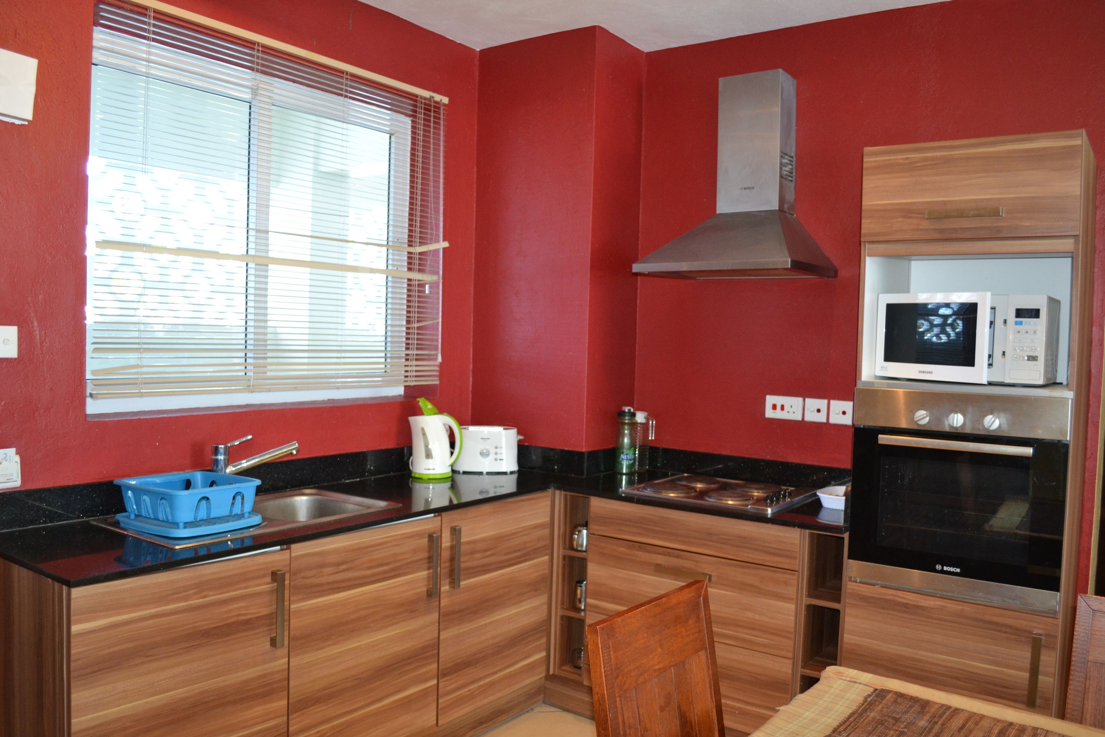 Eine kompakte Küche mit Holzausstattung, einem Edelstahlspülbecken, einer Mikrowelle und einem Bosch-Backofen.