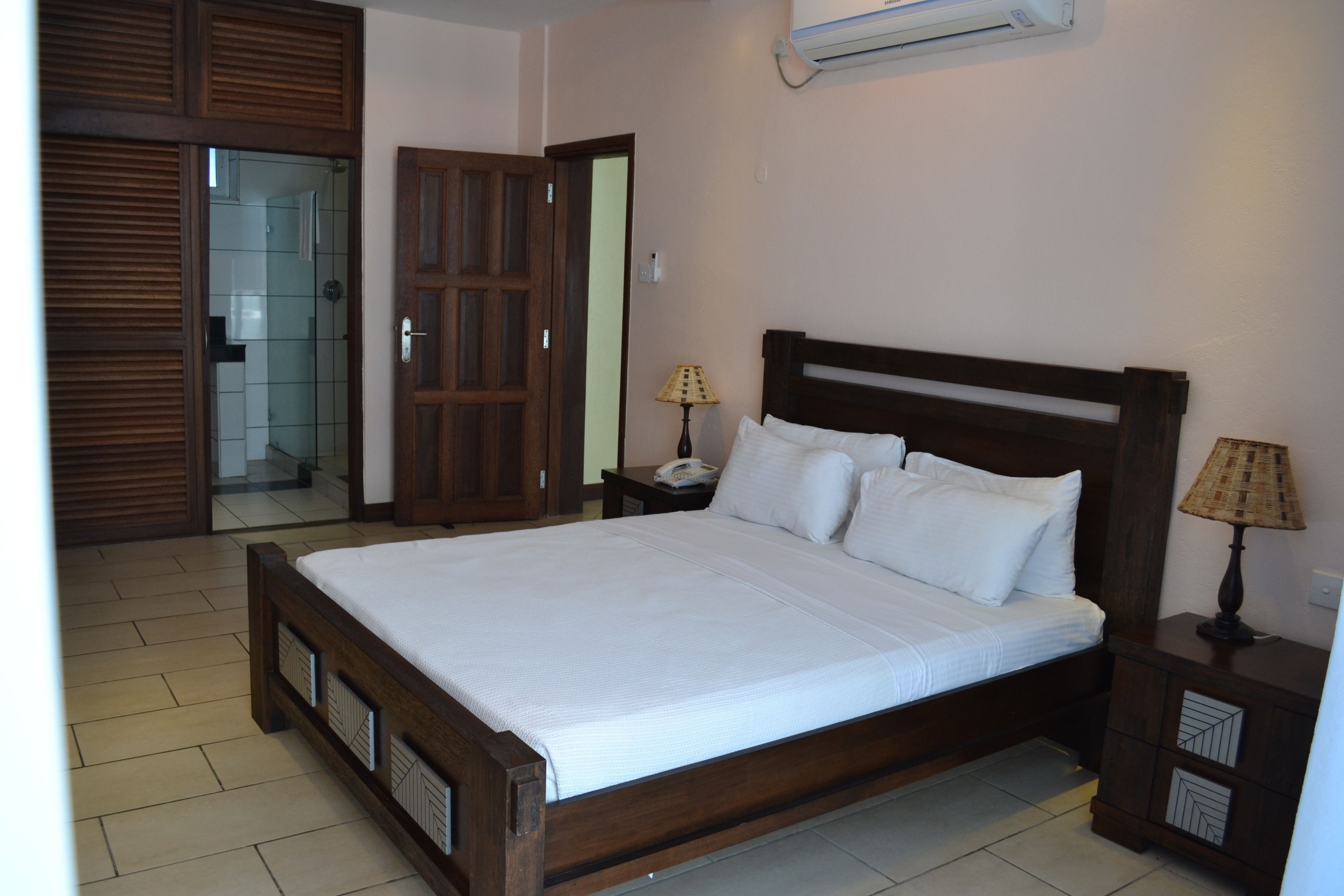 Un dormitorio con cama de madera, mesita de noche, lámpara y armario.