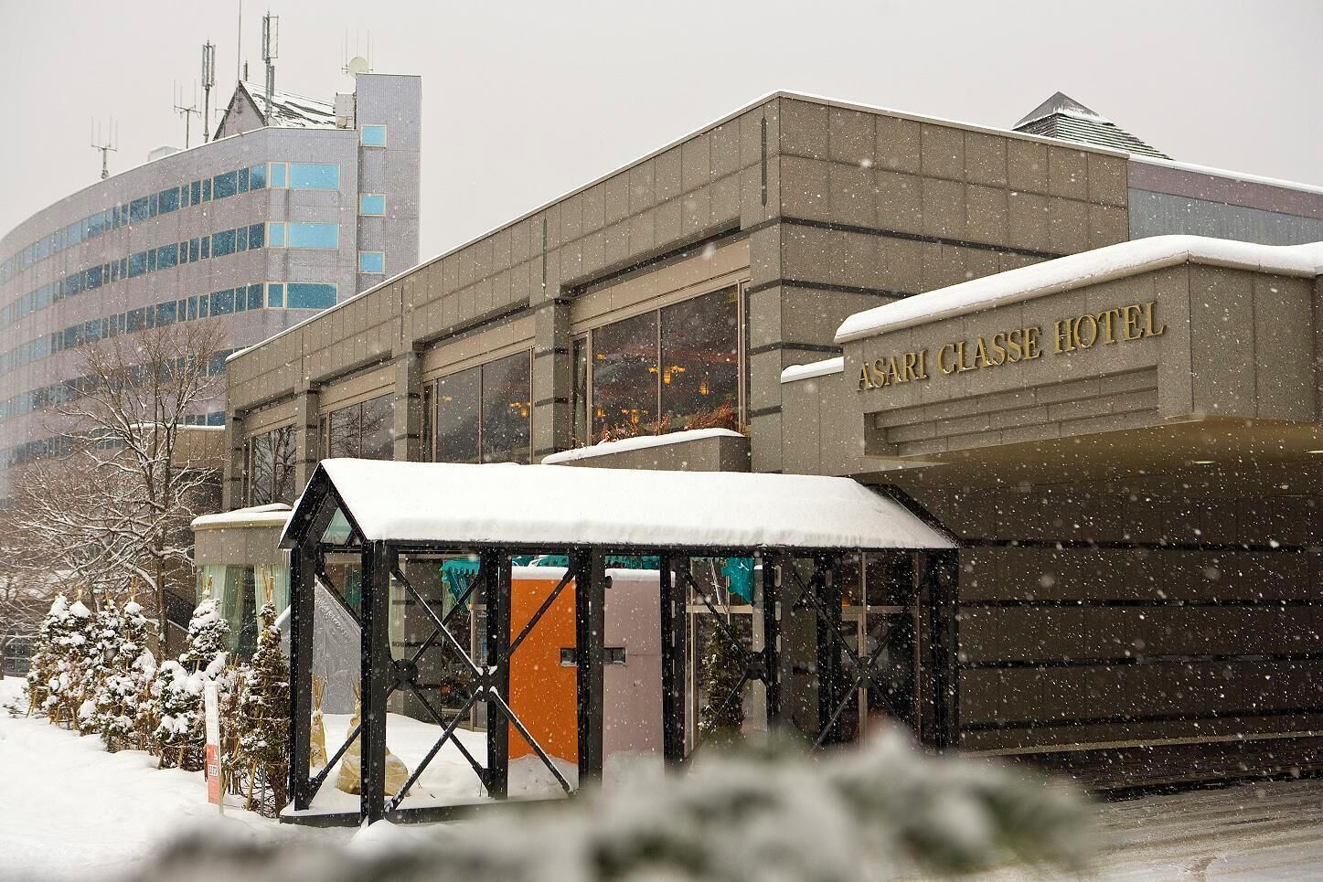 Das Asahi Classe Hotel mit überdachter Einfahrt und Schnee auf dem Dach.