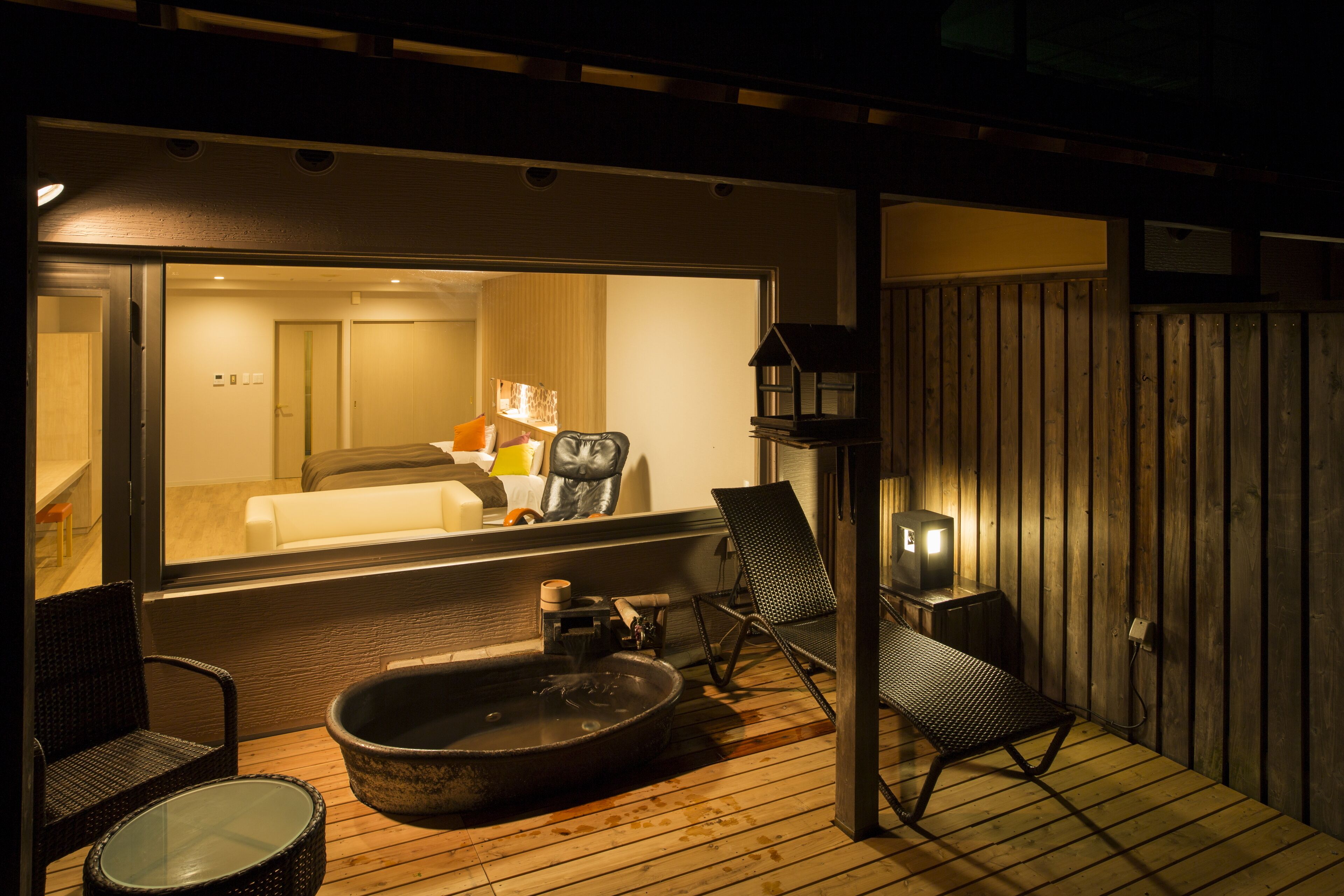 A wooden deck with a hot tub, lounge chairs, and a television.