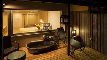 A wooden deck with a hot tub, lounge chairs, and a television.