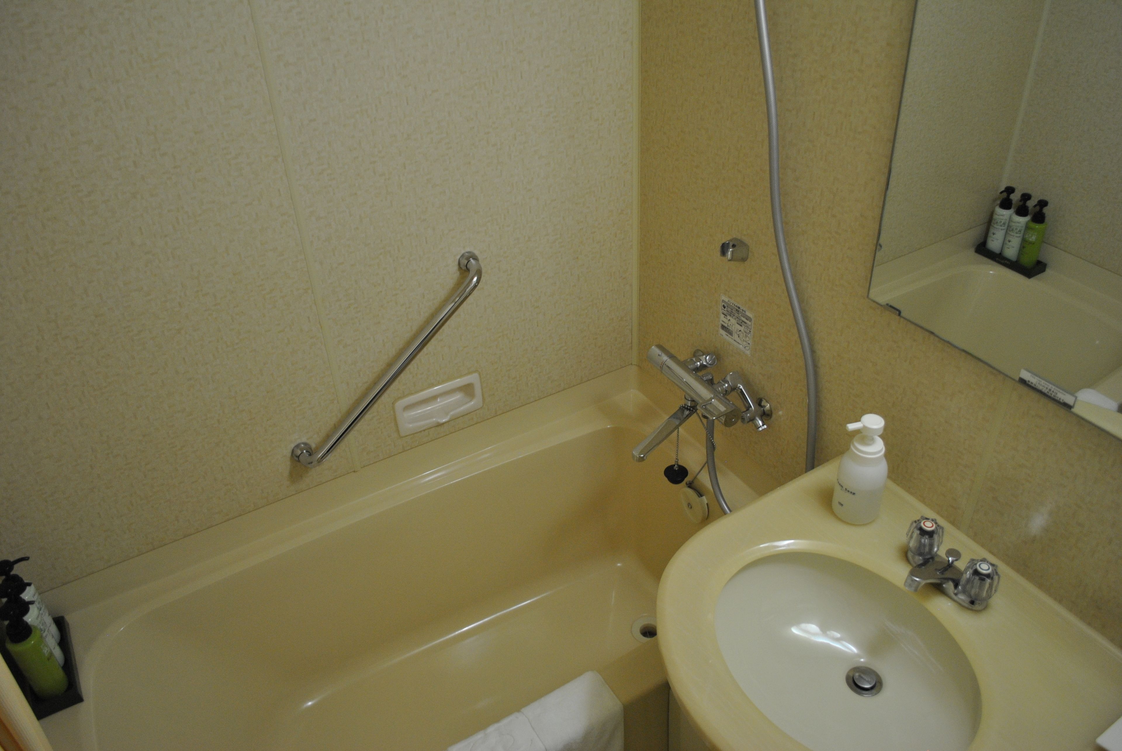 A bathroom with a bathtub, a sink, and a mirror.