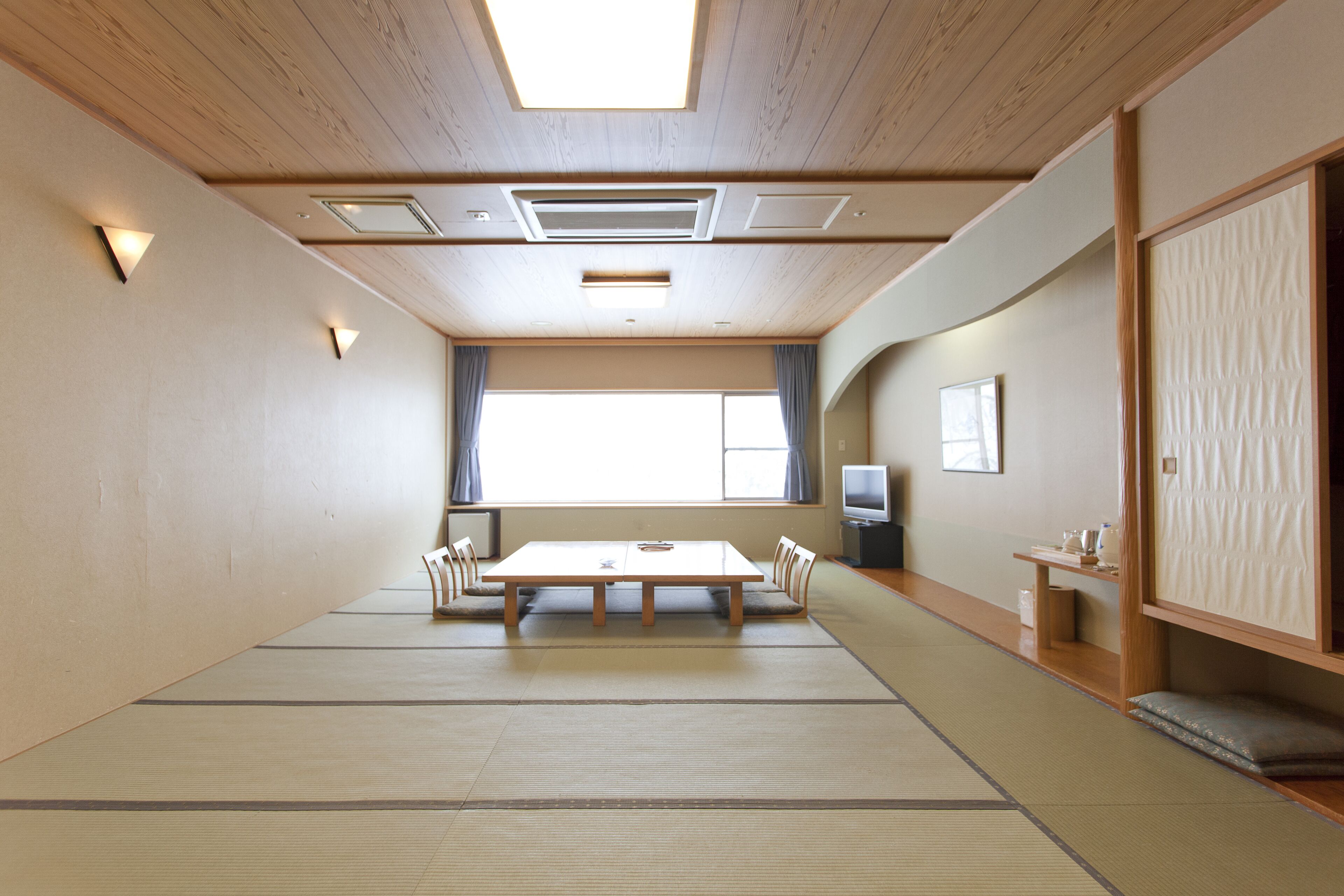 Una habitación tradicional japonesa con suelo de tatami, una mesa baja y puertas correderas.