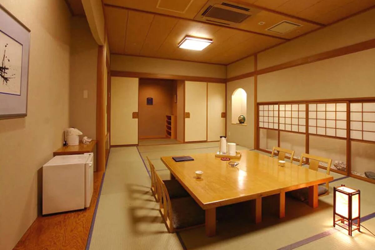 A traditional Japanese-style room with tatami flooring, a wooden table, and shoji screens.