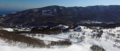 A snow-covered landscape with a winding road, mountains in the background, and a clear sky.
