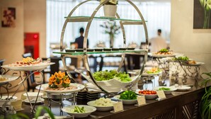 A buffet setup with various dishes, including salads, vegetables, and a decorative centerpiece. - Super Candle Hotel (Hanoi)