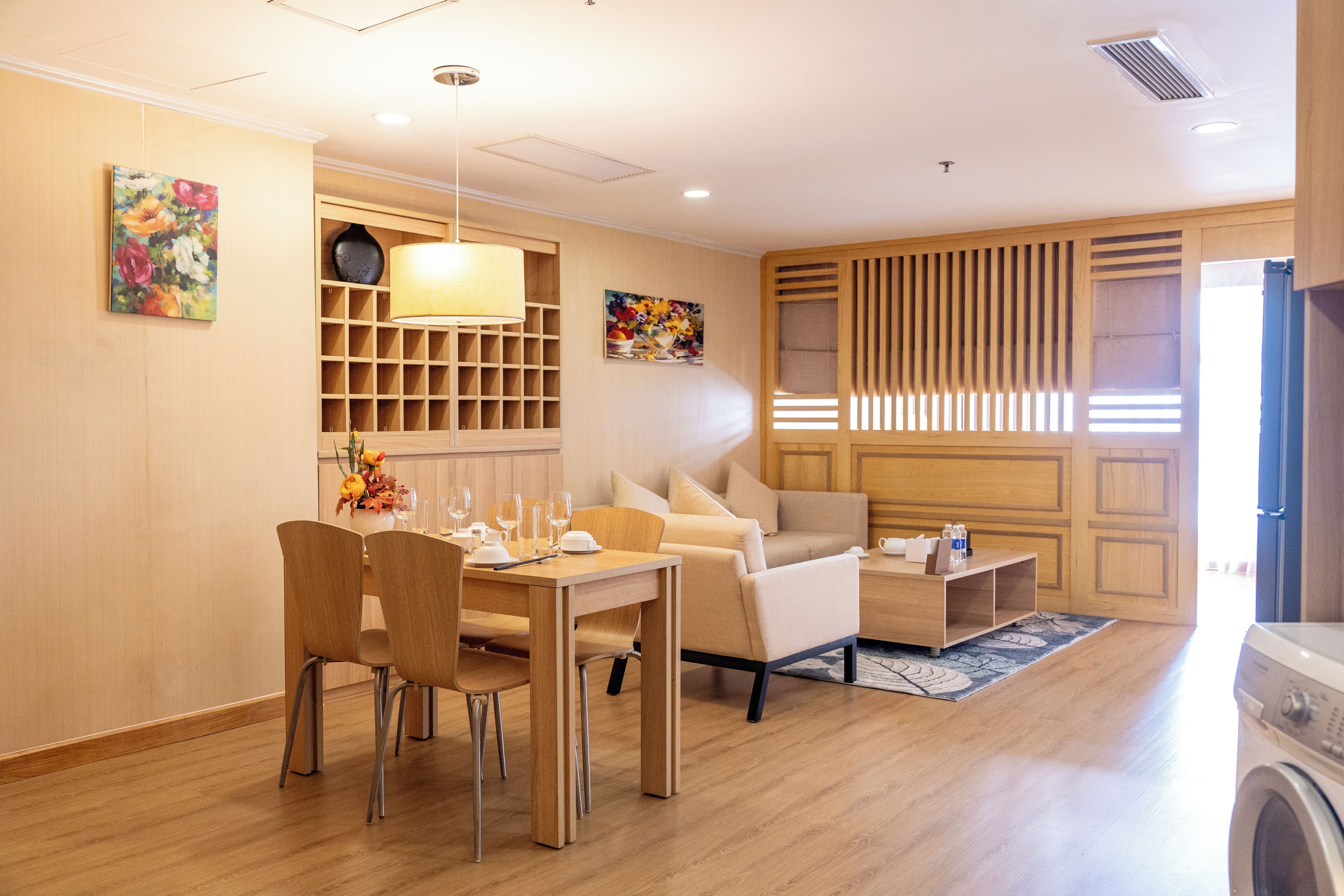 Un salon moderne avec un coin repas, un plancher en bois et un lave-linge.