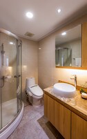 Un baño moderno con ducha envuelta en vidrio, un inodoro y un lavamanos con espejo superior.
