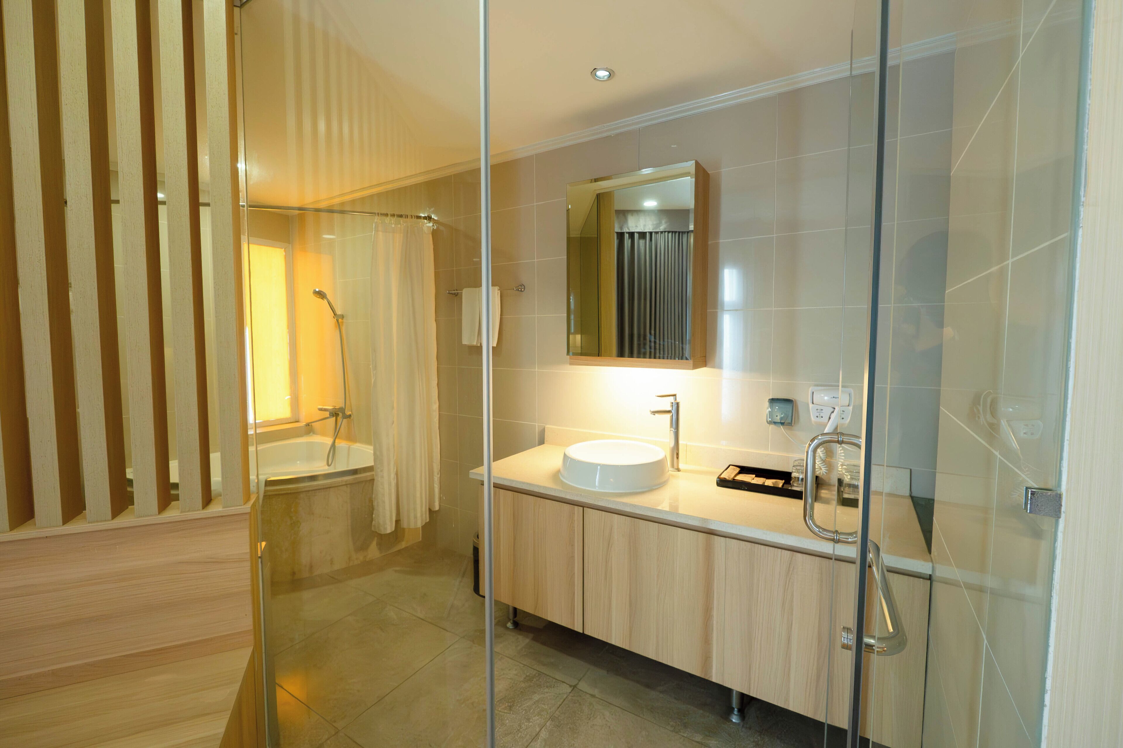 A modern bathroom with a glass shower enclosure, a white sink, and a mirror above it.