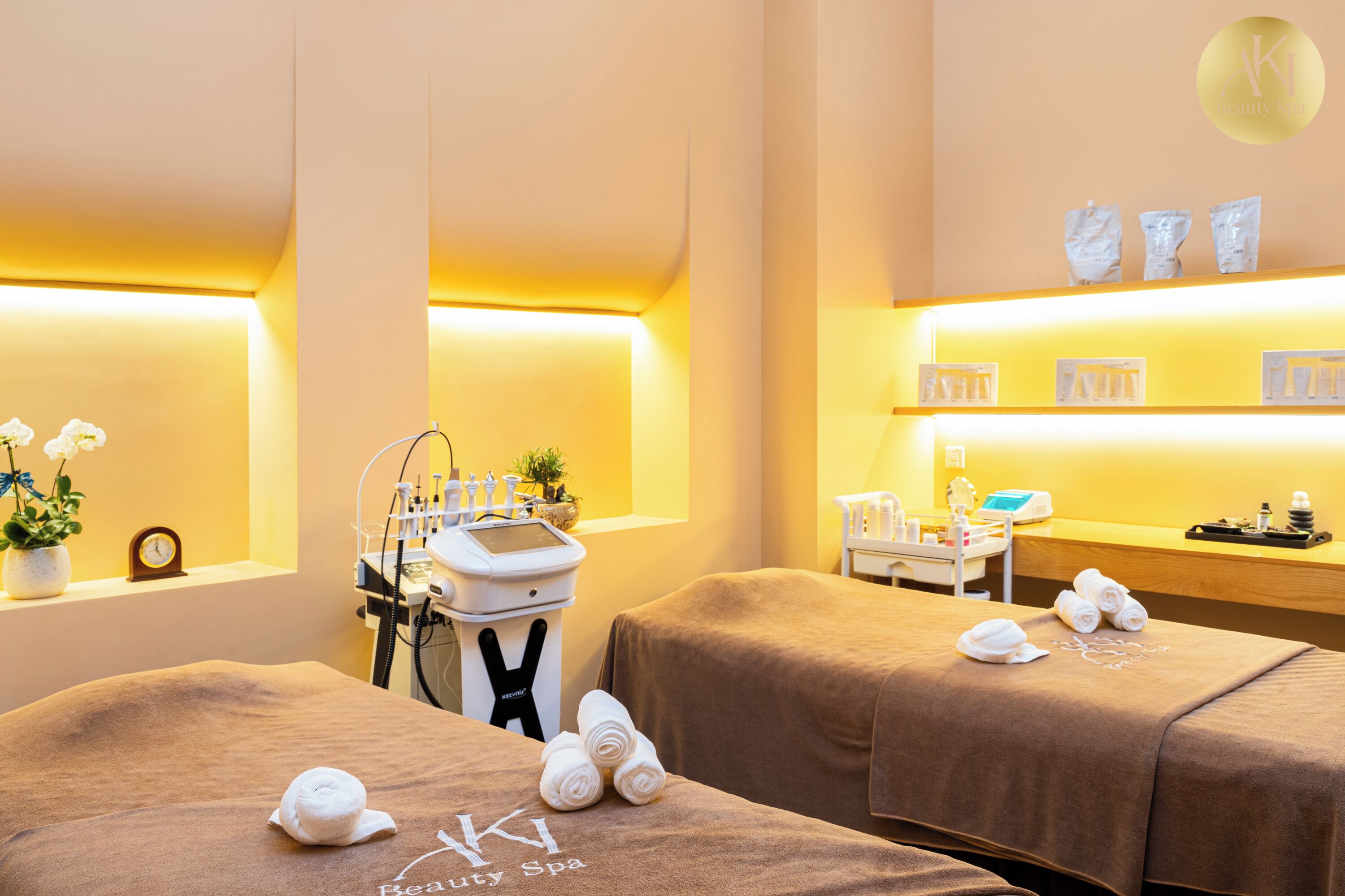 A spa room with two massage tables, towels, a clock, and a reception desk.