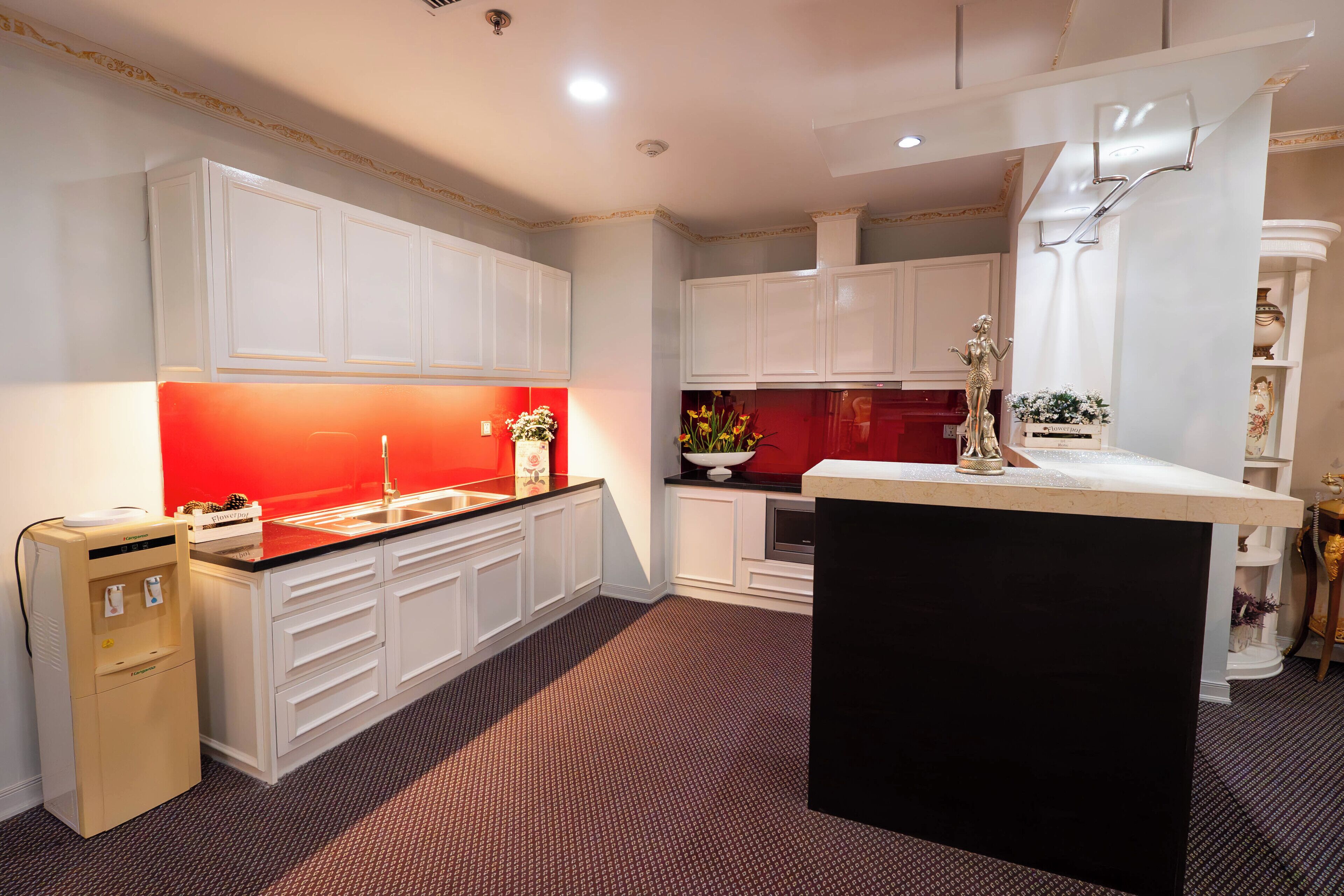 Une cuisine moderne avec des meubles blancs, un pare-feu rouge et un îlot central.