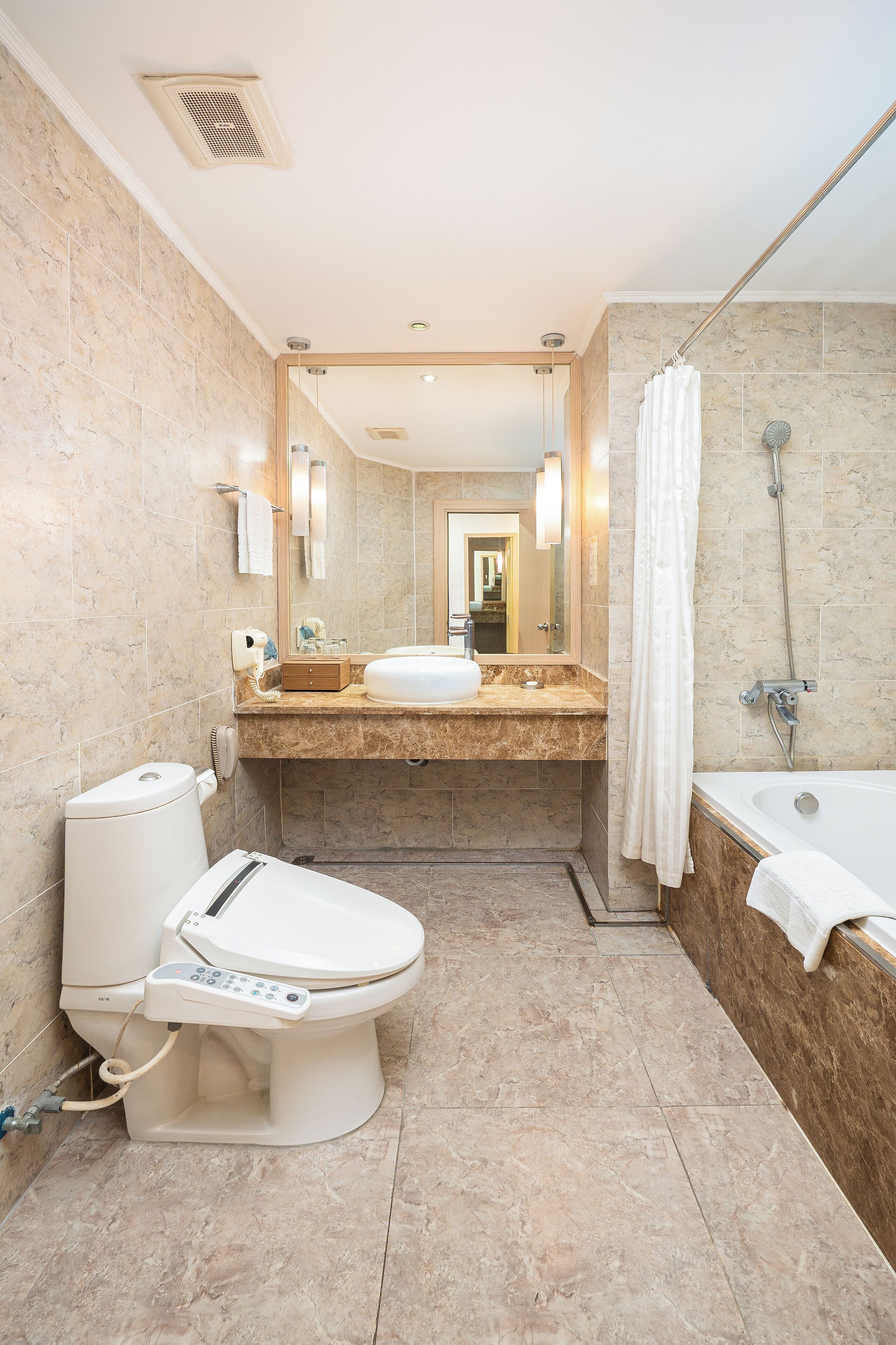A modern bathroom with a toilet, bidet, sink, and bathtub.