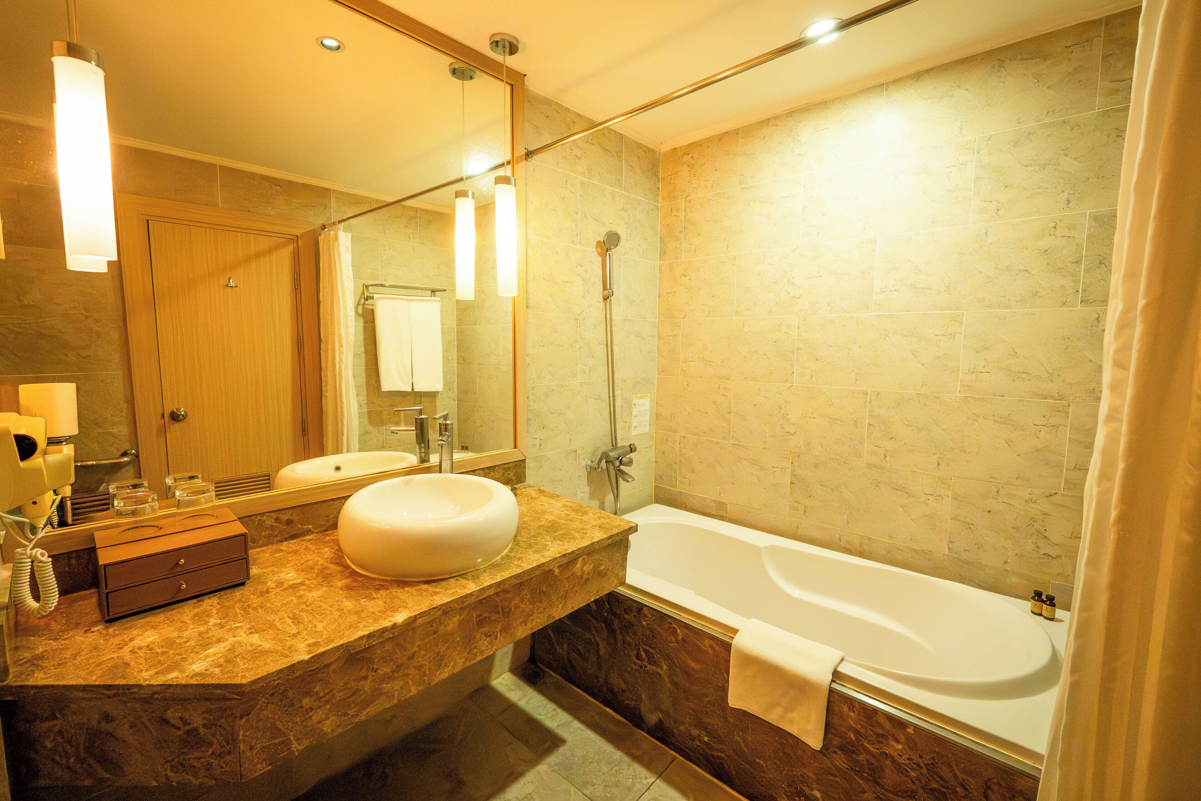 A modern bathroom with a marble vanity, a large mirror, a bathtub, and a shower.