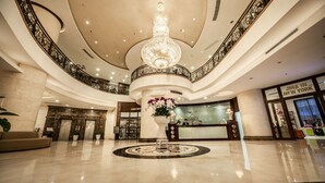 A grand lobby with a large chandelier, a reception desk, and a circular marble floor. - Super Candle Hotel (Hanoi)