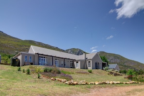 Enjoy the expansive views from the covered patio area, surrounded by a grassy hill and a rocky outcrop.