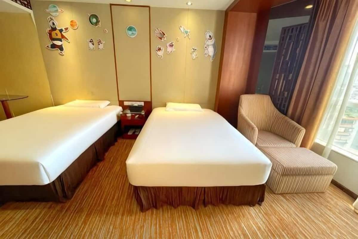A hotel room with two beds, a sofa, a small table, and a wall with decorative items.
