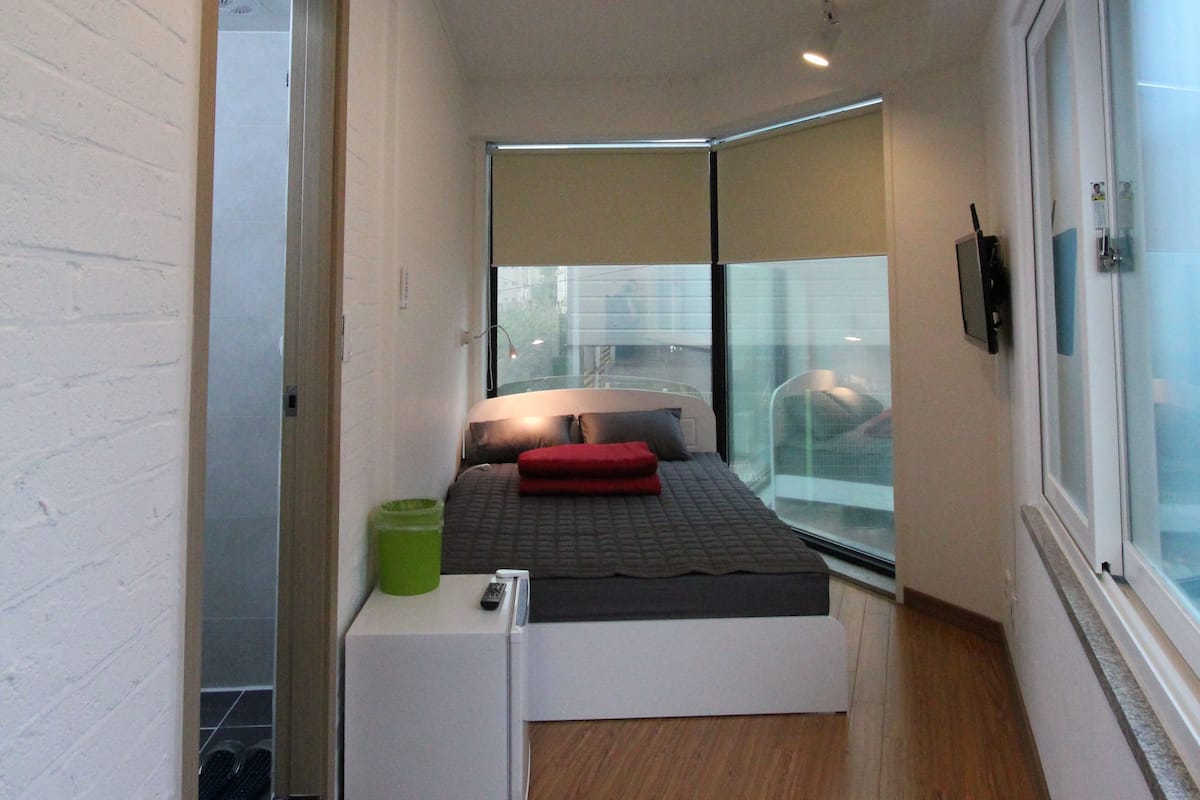 A narrow hallway with a bed at the end, a small table, and a window with a view.