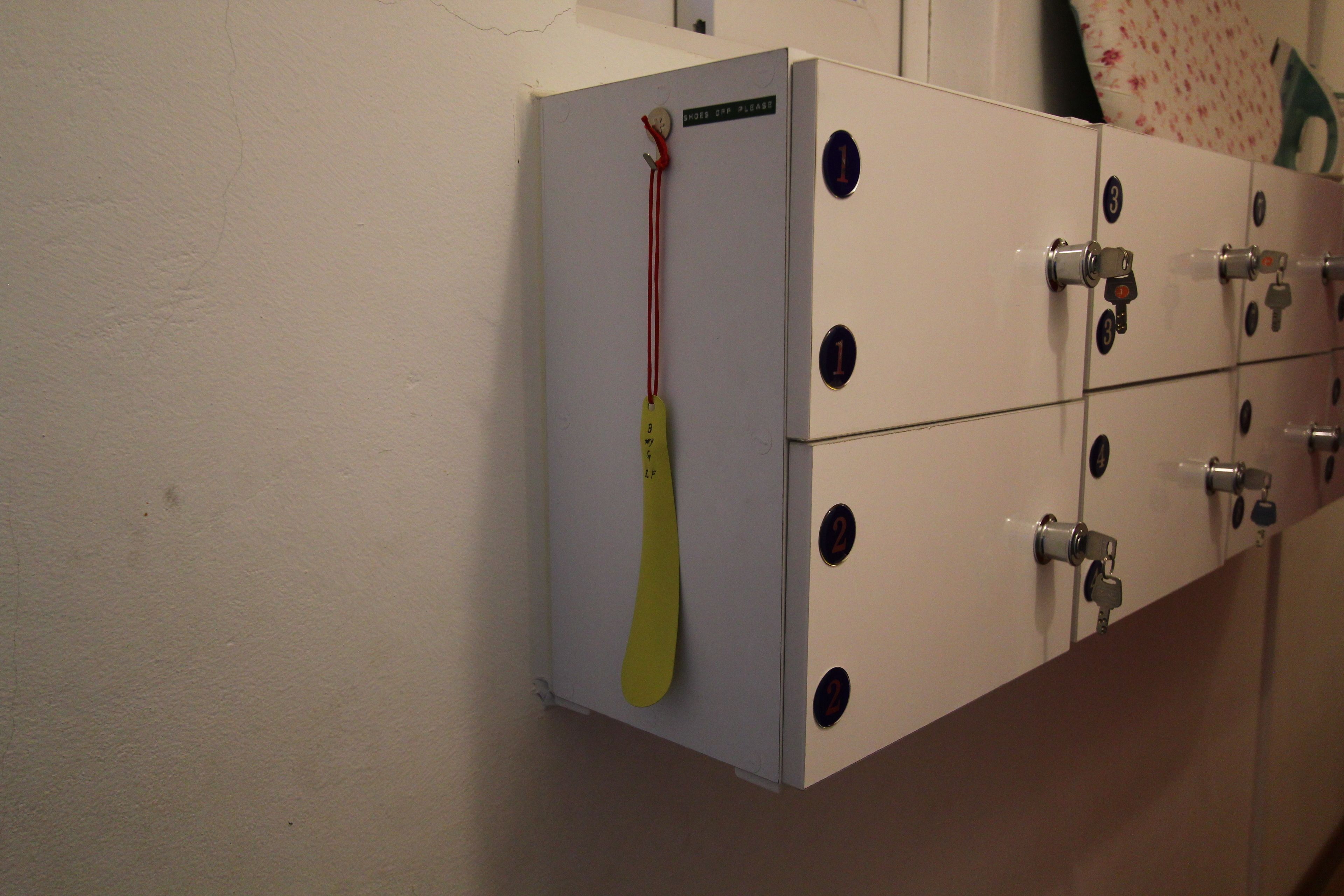 A set of white lockers with numbered compartments and a yellow keychain hanging from one.