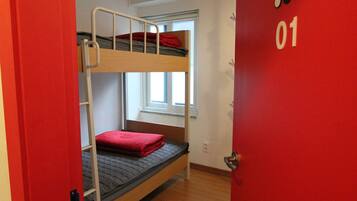 A bunk bed room with a red door labeled "01" and a window with a view of the outside.