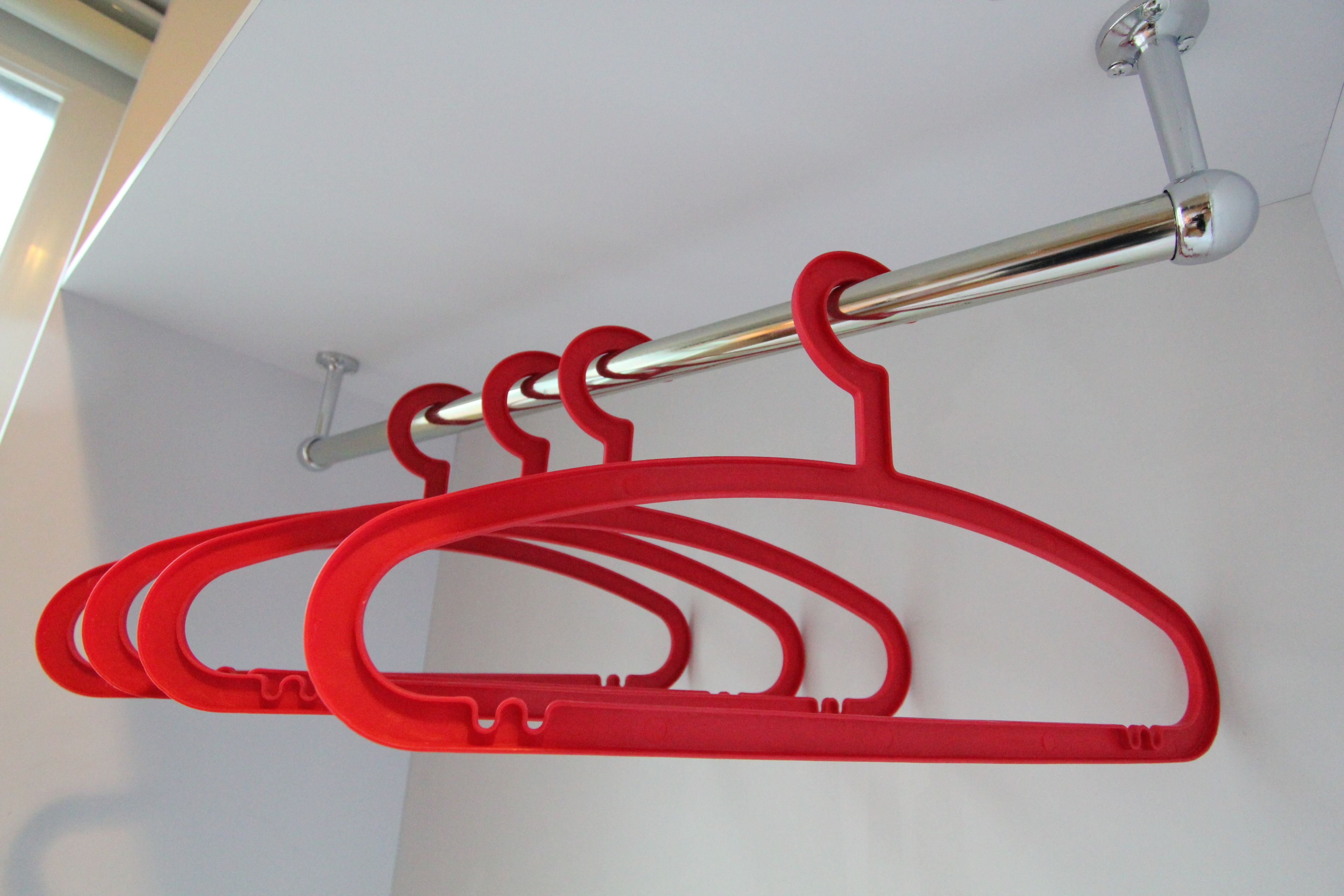 Una barra de metal con perchas de plástico rojas.