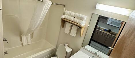 A bathroom with a bathtub, toilet, sink, and a mirror.