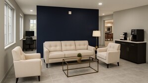 A modern living room with a beige sofa, two armchairs, a coffee table, and a dark accent wall. - Baymont by Wyndham Dickinson (Dickinson)
