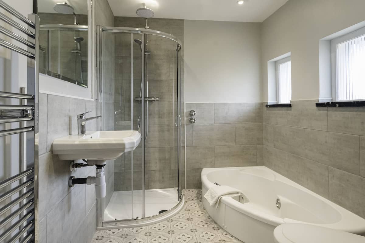 Une salle de bain moderne dotée d’une douche à parois de verre, d’une baignoire sur pieds et d’un lavabo avec un miroir au-dessus.