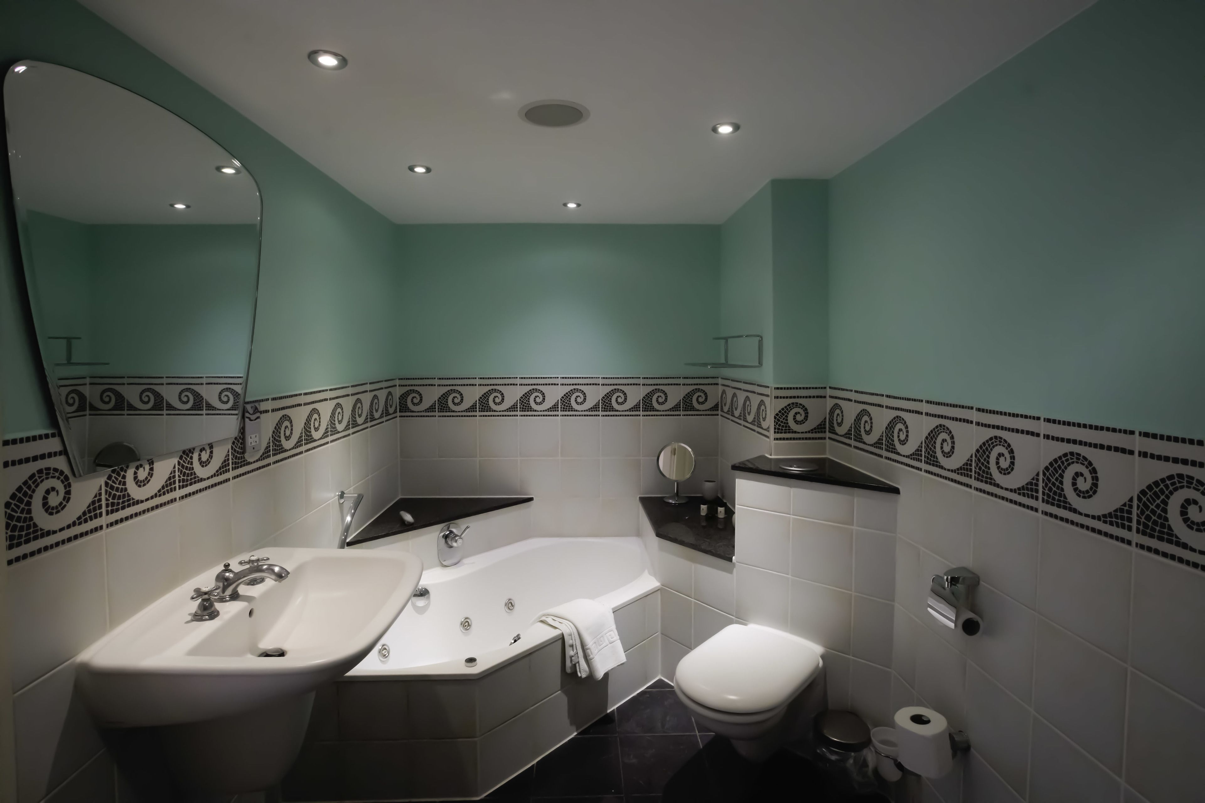Un baño con lavamanos, bañera, inodoro y espejo.