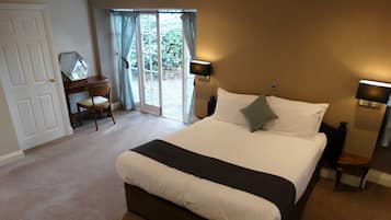 Habitación de hotel con una cama grande, un escritorio con silla y vistas a través de la puerta de cristal.