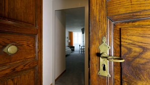 A wooden door with a brass handle leading to a room with a bed, a chair, and a window with curtains. - Hotel Roter Ochsen (Solothurn)