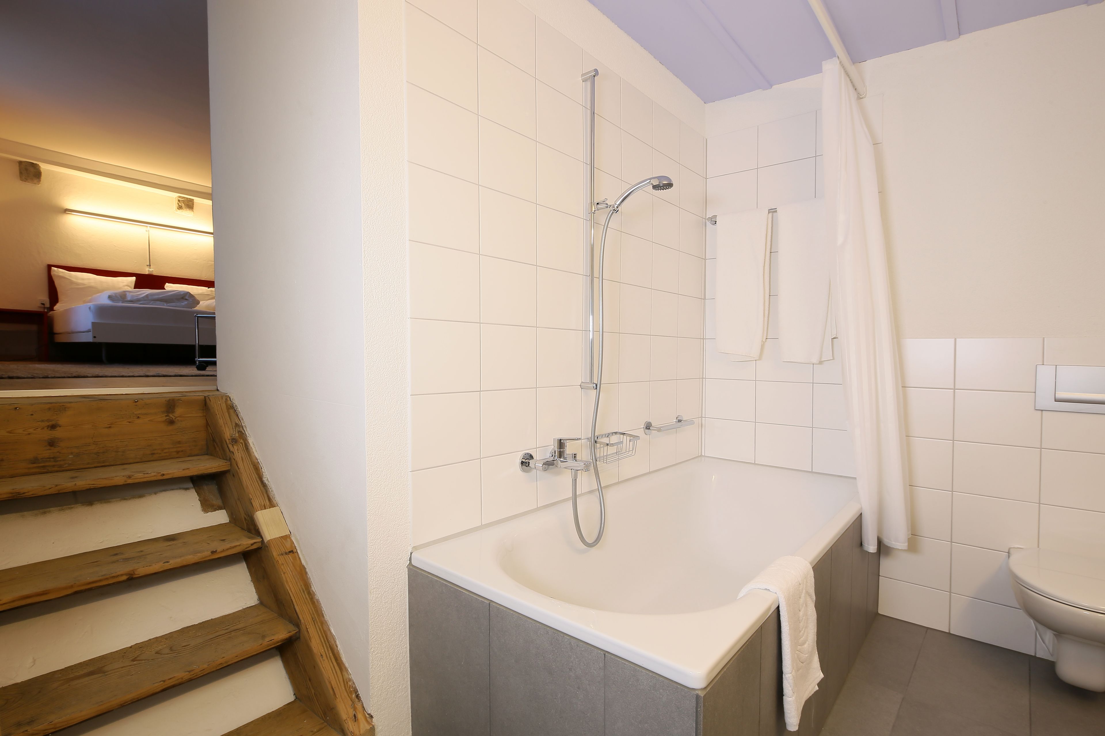 Een moderne badkamer met een bad, douche en toilet.