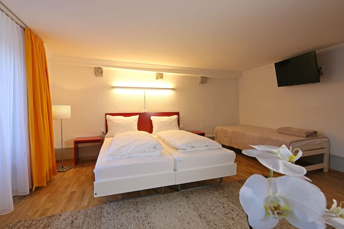 A hotel room with a bed, bedside tables, a TV, and a small desk.