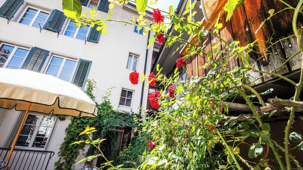 A narrow street with buildings, a wooden fence, and a red flower bush. - Hotel Roter Ochsen (Solothurn)