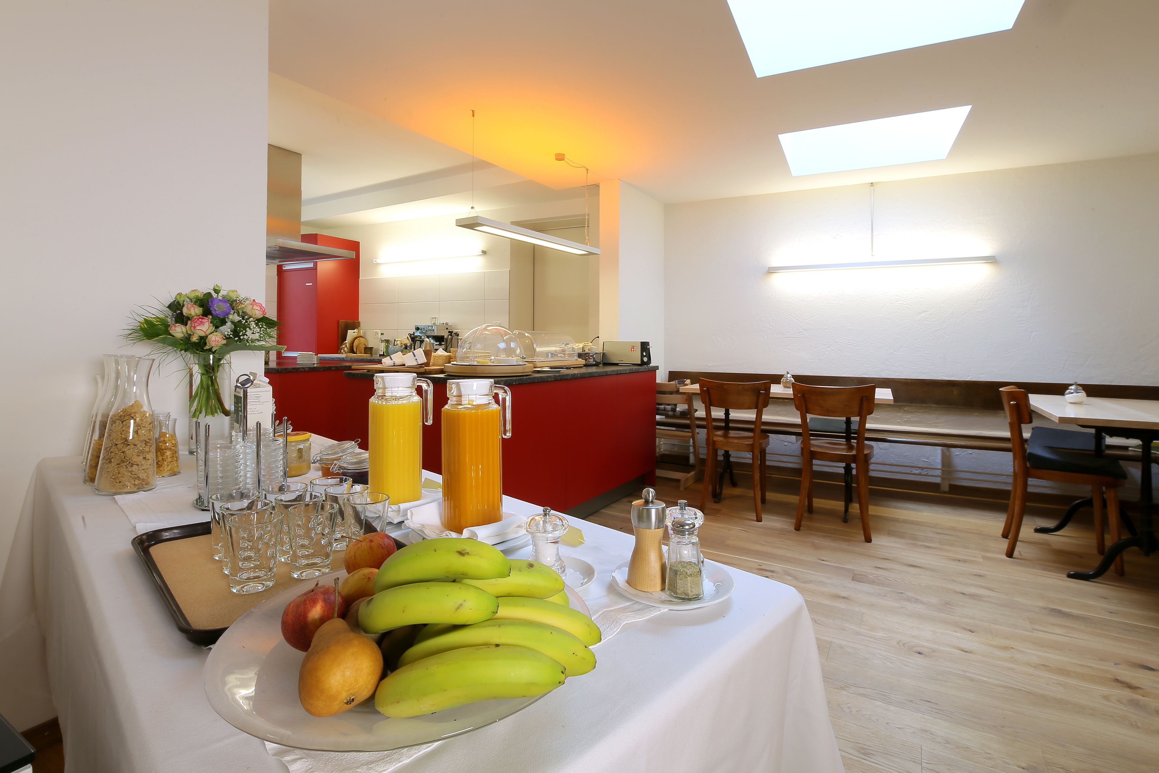 A breakfast buffet with fruits, beverages, and condiments.
