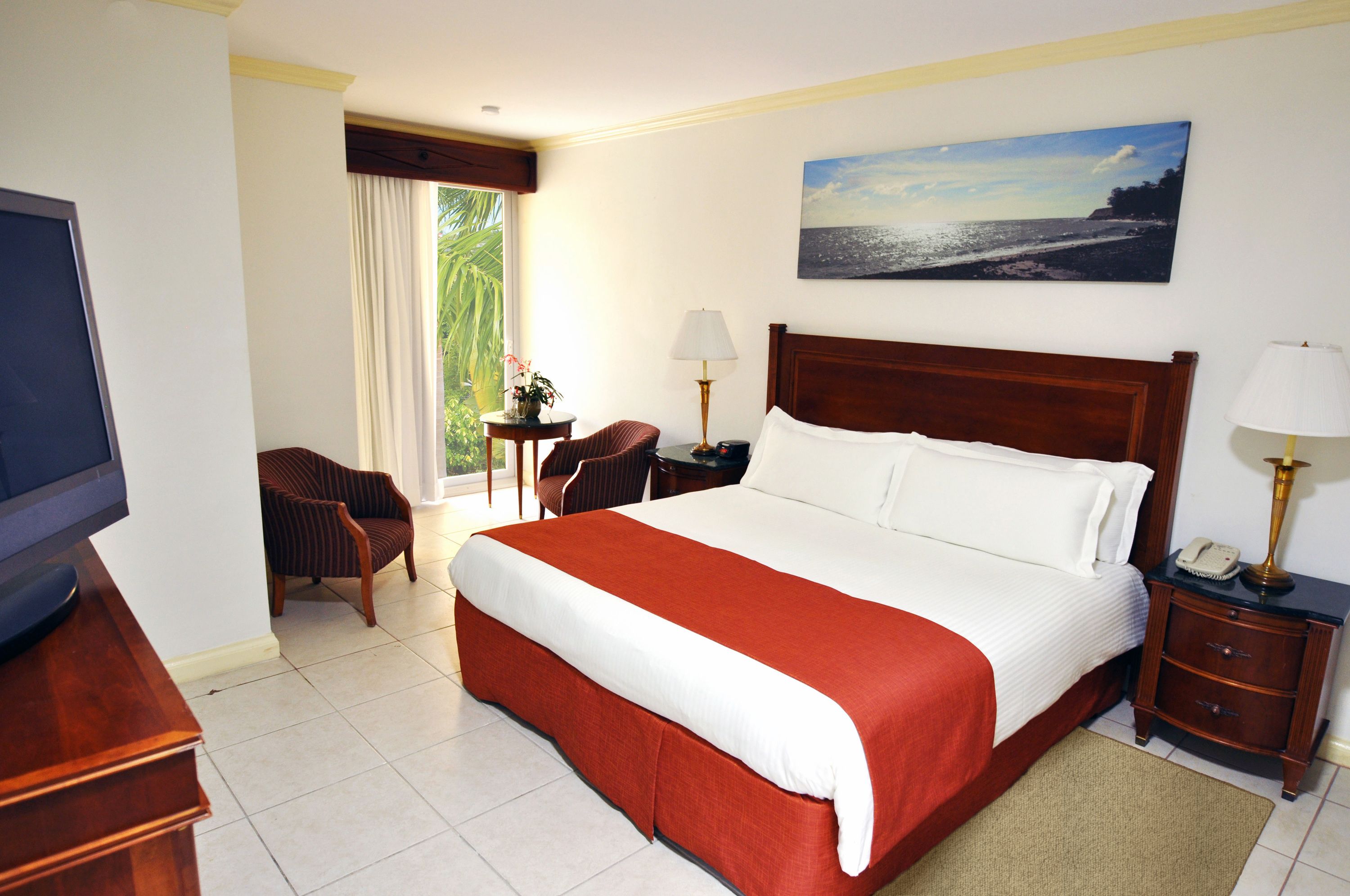 A hotel room with a large bed, a TV, a desk, and a chair.