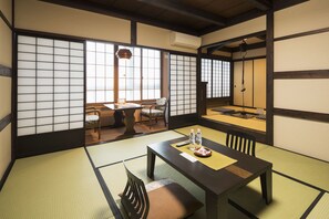 A traditional Japanese room with tatami flooring, a low table with a tray, and a view through shoji screens.