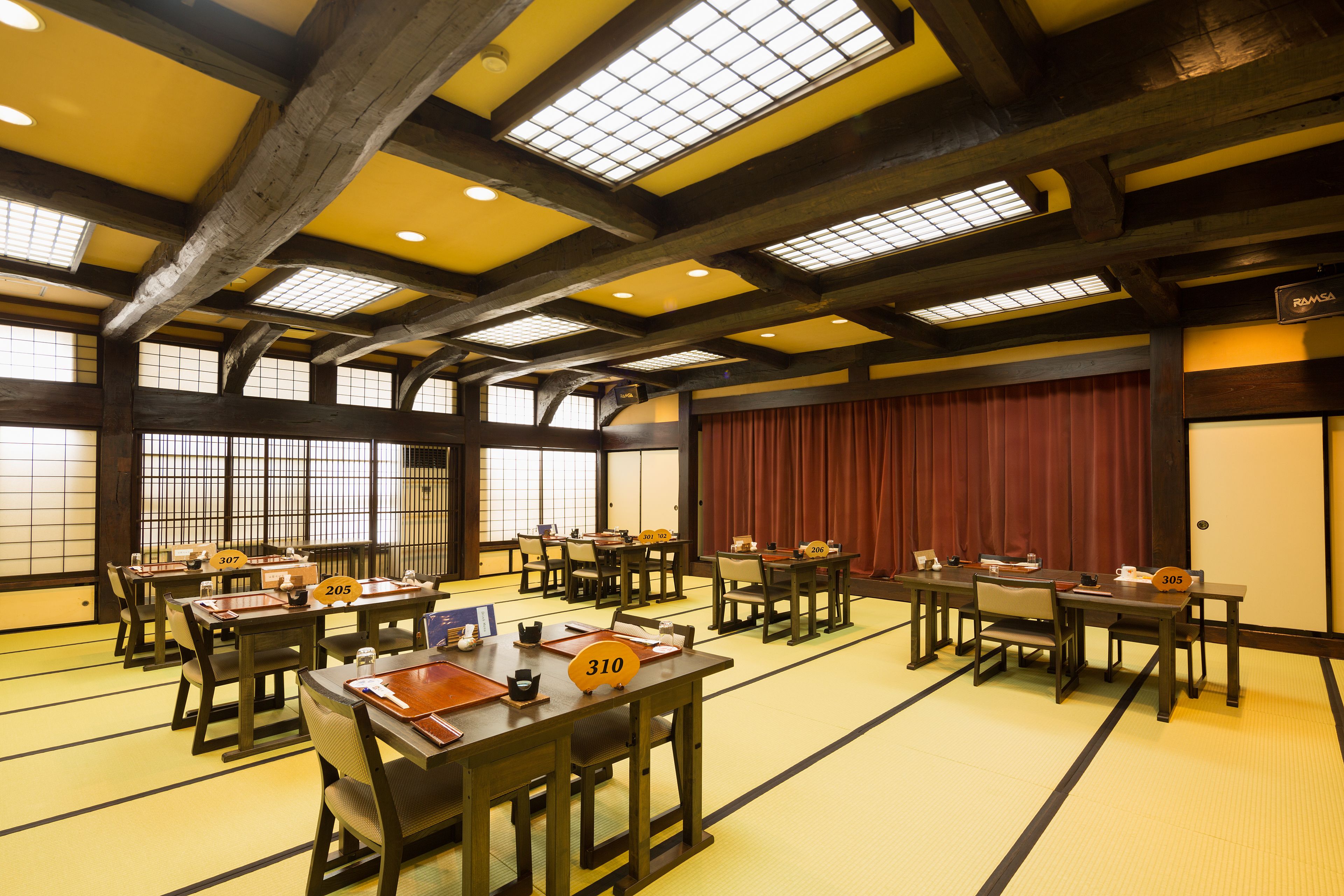 A traditional Japanese-style room with tatami mat flooring, wooden tables, and sliding doors.