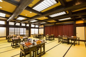 A traditional Japanese-style room with tatami mat flooring, wooden tables, and sliding doors.