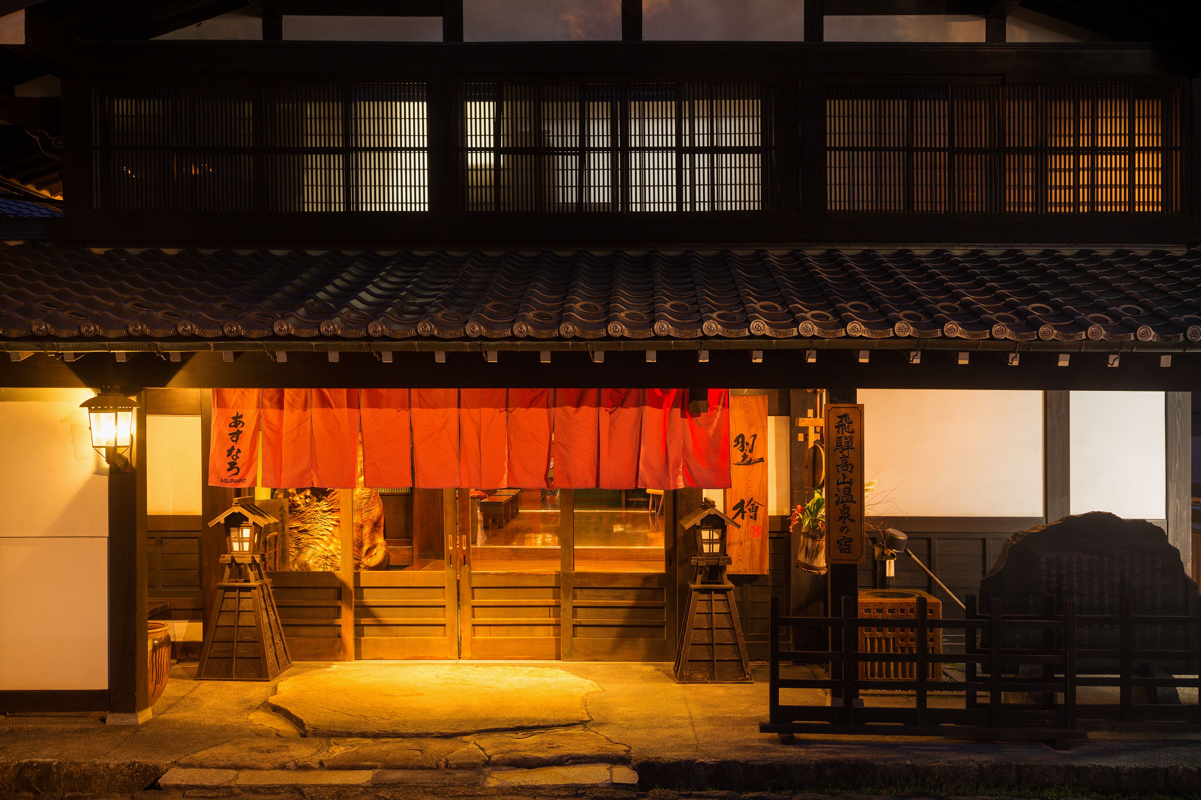 Un edificio japonés tradicional con tejado de tejas, puertas de madera y toldo rojo.