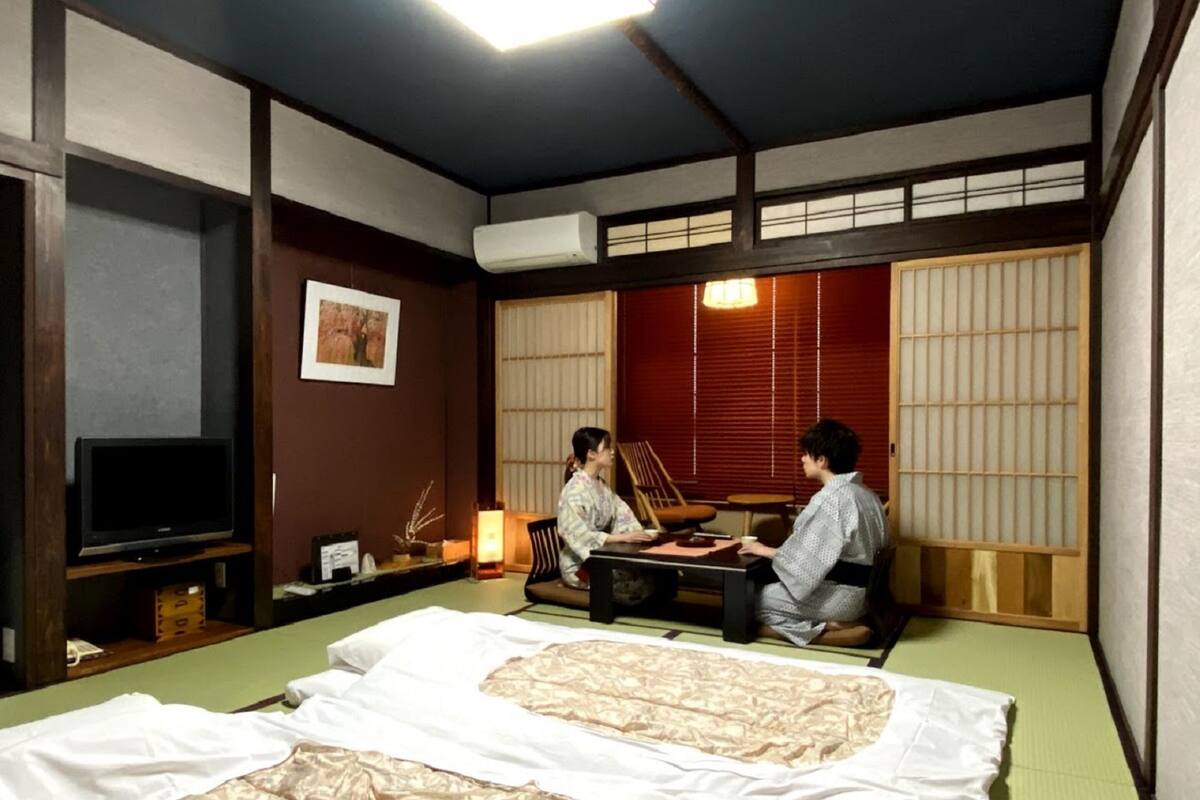 Une pièce de style japonais traditionnel, avec un sol recouvert de tatamis, une table basse et un téléviseur posé sur une étagère.