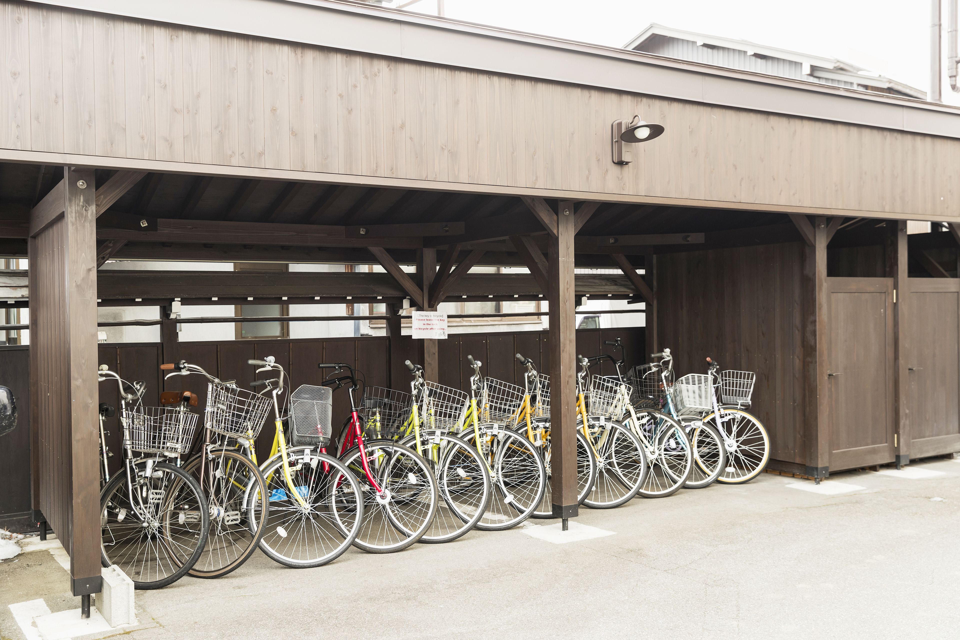 Un espace de stationnement pour vélos abrité, où sont garés plusieurs vélos, et une signalisation indiquant une durée maximale de stationnement de 15 minutes.