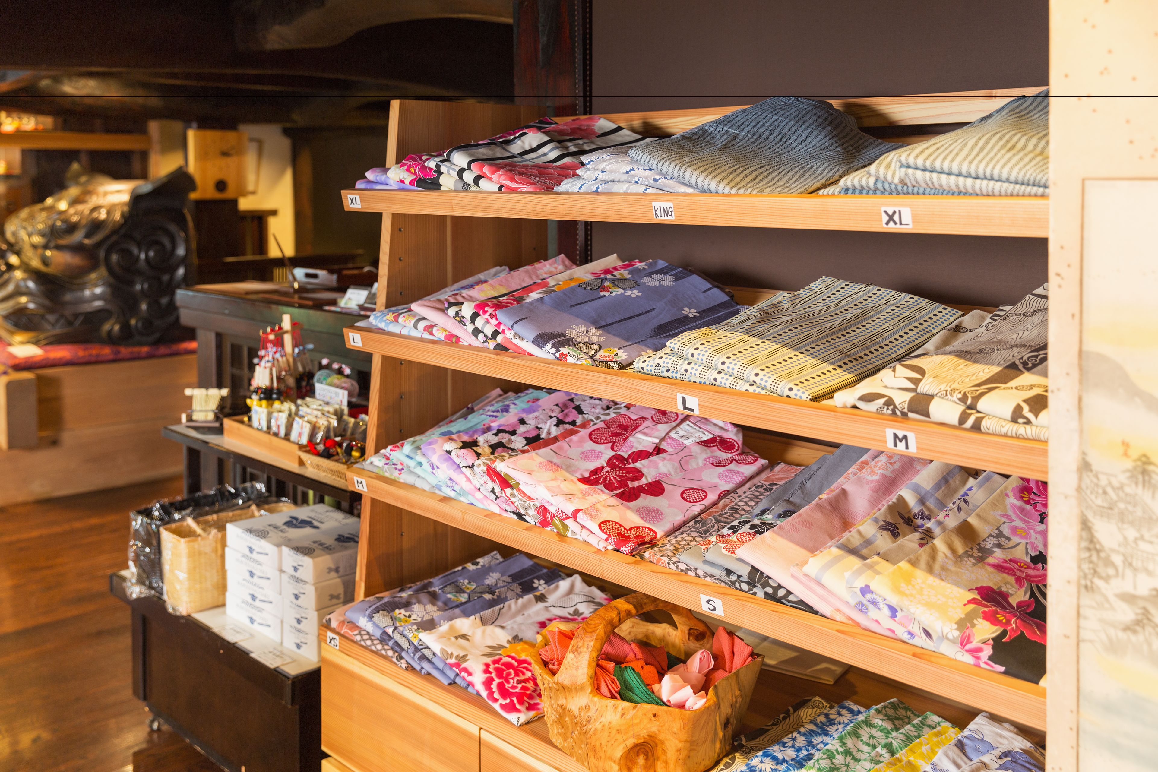 A store with shelves of folded fabrics and a wooden display case with boxes.