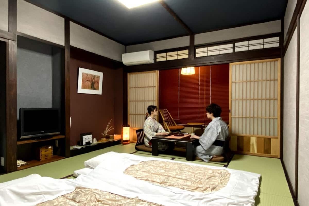 Une pièce de style japonais traditionnel, avec un sol recouvert de tatamis, une table basse, un téléviseur et une porte coulissante.