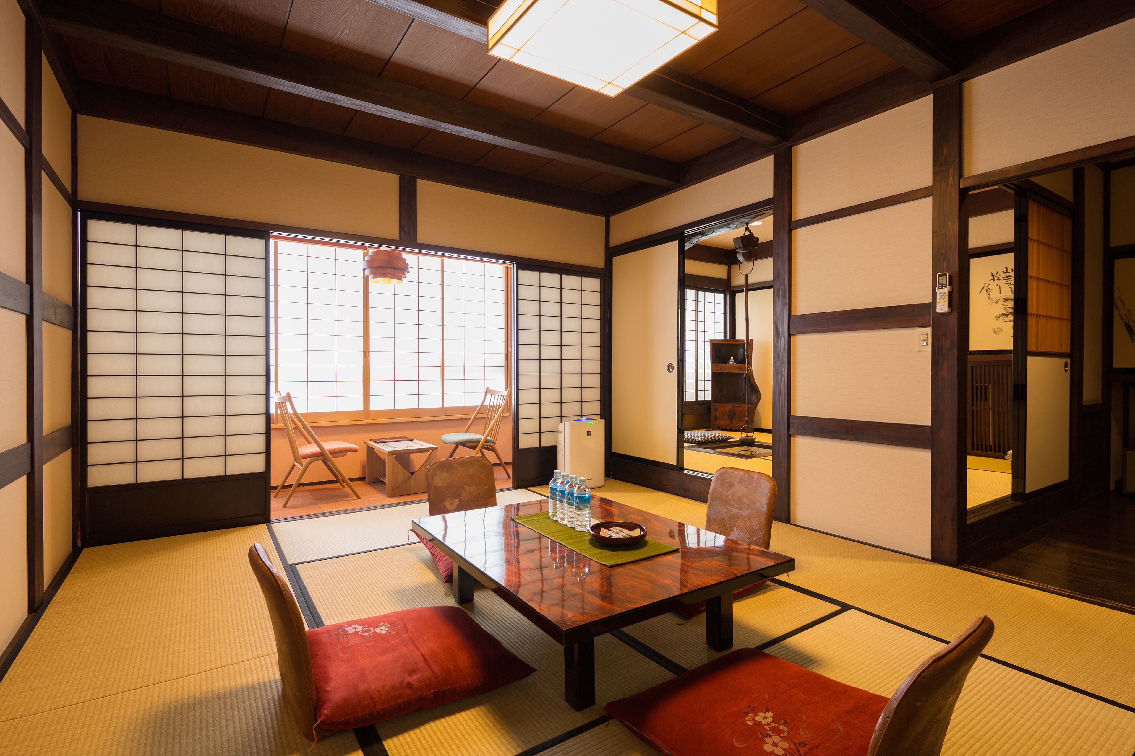 A traditional Japanese room with tatami flooring, a low table with cushions, and sliding doors.