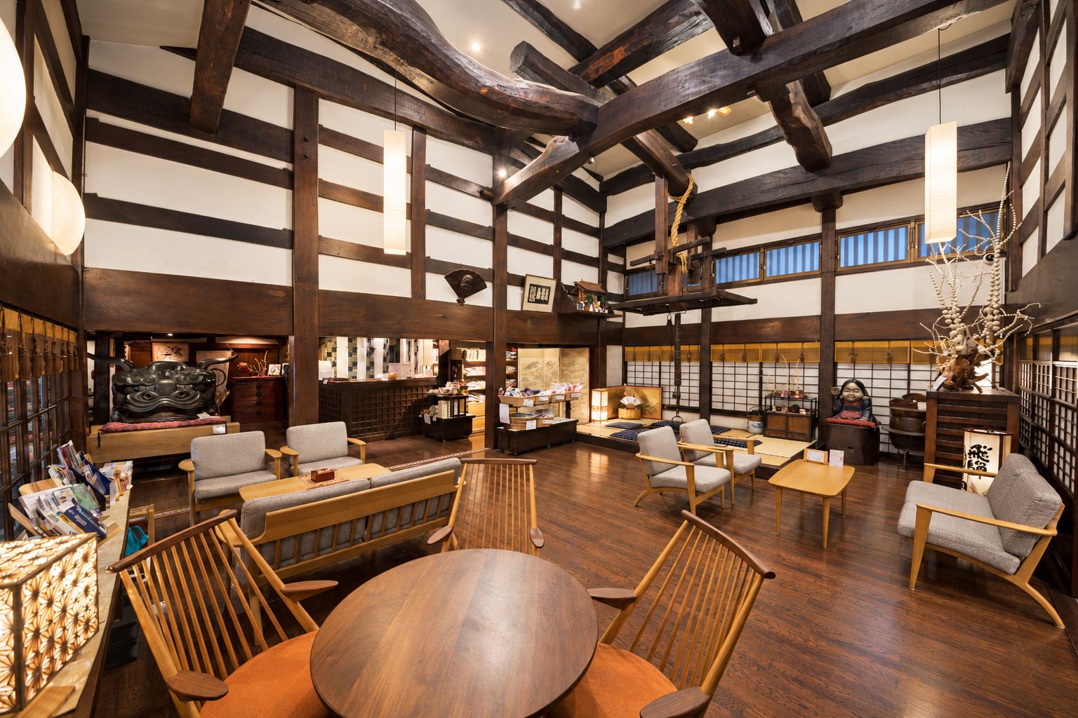 A spacious interior with high ceilings, exposed wooden beams, and a variety of seating arrangements including sofas and chairs.