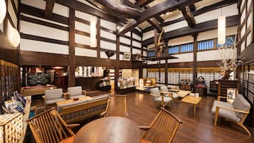 A spacious interior with high ceilings, exposed wooden beams, and a variety of seating arrangements including sofas and chairs.